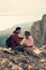 Couple is sitting on the stones, resting, admiring each other and the view, enjoying the fresh air.