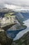 Couple sitting on trolltunga troll`s tongue rock , Norway