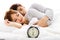 couple sleeping in bed next to an alarm clock
