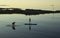 A couple slowly paddle their surf boards in the calm sea at Groomsport harbour near Bangor Northern Ireland