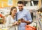 Couple with smartphone buying olive oil at grocery