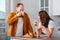 Couple of smiling young people man and woman having breakfast in kitchen at home. Married couple drinking coffee and