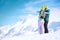 Couple of snowboarders pointing to volcano in front of snowy mountains