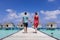 Couple spending romantic beach vacation holidays at luxurious resort in Maldives with overwater villas, turquoise sea water and