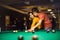 Couple spending time in billiard room. Boyfriend teaching his girlfriend to playing billiard