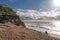 A couple stand on the beach by dramatic sunlit cliffs at West Bay, Dorset, UK.