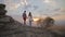 Couple stand on rock and watching sunset on top of the mountain