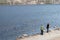 The couple stand on the rocks and looking to the  flock of wild ducks swimming in the Yenisei river against the rocky shore