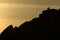 A couple stand silhouetted against a sunset atop stanage edge