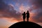 Couple standing on hill in sunset sky