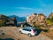 couple standing near car looking at meteora monastery Thessaly mountains Greece