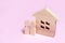 A couple is standing near a house on a pink background. The concept of love and faithfulness, home comfort. Buying and selling re