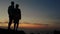 Couple standing on the outcrop on a windy evening watching sunset