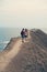 Couple is standing on the promontory of the sea, taking a photo, enjoying the view and fresh air.