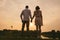 Couple standing on a river shore, watching a beautiful sunset taking place.