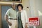 Couple Standing By Sold Real Estate Sign