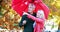 Couple standing under umbrella in park