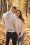 Couple stands in the forest together. Attractive girl hugging her boyfriend and looking at the camera. Happy family stay