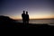 Couple strolling by the sea at sunset on a beach, silhouette