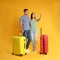 Couple with suitcases for summer trip on yellow background. Vacation travel