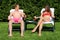 Couple sunbathing in back yard and drinking cocktails