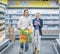 Couple in a supermarket shopping with full food cart buying groceries