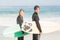 Couple with surfboard standing on the beach