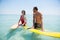 Couple with surfboard standing in sea
