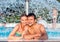 Couple in swimmning pool under splashing fountain. Summer heat.