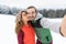 Couple Taking Selfie Photo On Smart Phone Snowy Village Wooden Country House Man Woman Winter Snow