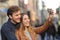 Couple taking selfie photo with a smart phone in the street