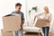 Couple Talking Joyfully Carrying Moving Boxes Into New Apartment