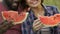 Couple tasting fresh watermelon during outside date in park, healthy nutrition