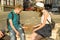 Couple of teenagers relaxing and playing a board game throwing dice, city street background