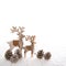 Couple of thw wooden deer with fir cone on white wooden backgrou