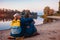 Couple of tourists with backpacks relaxing by autumn river bank. Sportive women travelling together. Family time