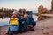 Couple of tourists with backpacks relaxing by autumn river bank. Sportive women travelling together. Family time