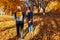 Couple of tourists with backpacks walking in autumn forest. Sportive women travelling together