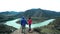 A couple of tourists are coming on top of a stone mountain, a fast mountain river flows below. Back view