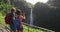 Couple tourists on Hawaii in USA by waterfall taking photo using phone