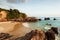 Couple tourists kayaking in tropical sea in the evening. Beautiful curved bay, beach, stone, rocks and waves. Fishermen and sunset