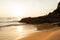 Couple tourists kayaking in tropical sea in the evening. Beautiful golden beach, stone, rocks and waves. Fishermen and sunset sky