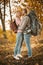 Couple of tourists in love in the autumn forest. Young man and woman kisses and hugs while standing against the backdrop