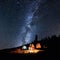 Couple tourists near campfire and tents under night sky full of stars and milky way