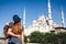 A couple of tourists a young man and a pretty woman embrace and look together at the world-famous Blue Mosque also