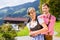 Couple in Tracht standing on meadow in alp mountains