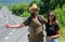 Couple travelers man and girl hitchhiking at edge road nature background. Travellers try to stop car. Hitchhiking is one