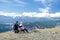 Couple travelers Man and Woman sitting on cliff relaxing mountains and enjoying valley view.