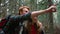 Couple trekking in forest. Redhead man showing woman wild animal in woods