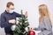 Couple trying to maintain social distancing while decorating Christmas tree